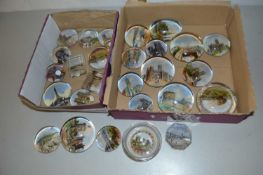 Two boxes of various early 20th Century paperweights decorated with scenes from various tourist