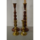 A pair of wooden barley twist candlesticks and a further pair of brass candlesticks