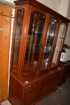 A glazed display cabinet with three glazed doors above, cupboards and drawers below