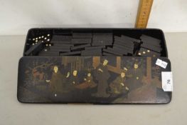 An Oriental black lacquered case of dominoes