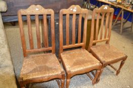A set of three oak framed and rush seated kitchen chairs