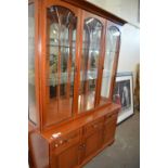 A glazed display cabinet with three glazed doors above, cupboards and drawers below
