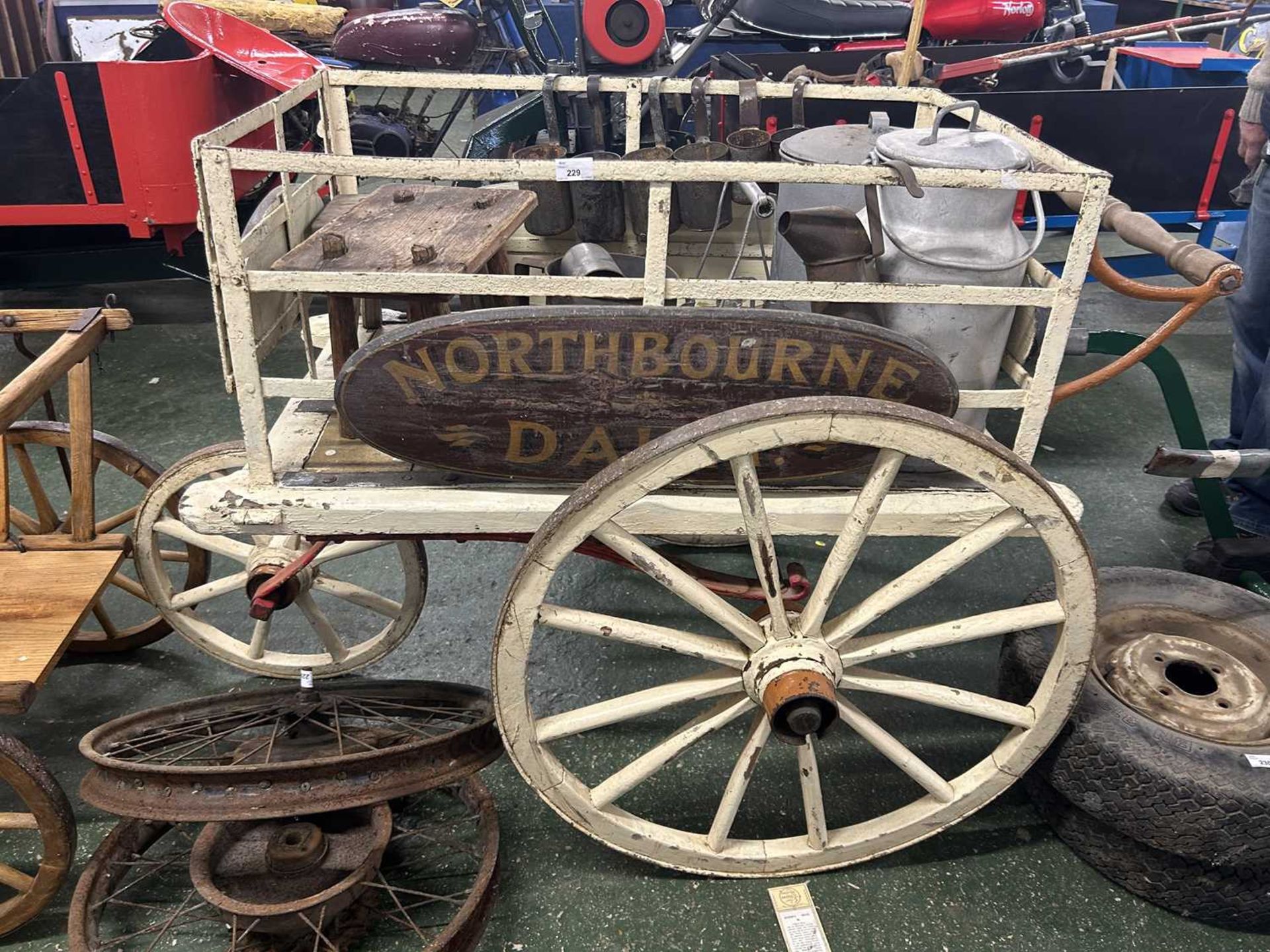 Vintage wood framed three wheel dairy cart bearing plaques for North Bourne Dairy containing a range