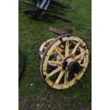 A pair of small yellow painted wood framed wheels with iron mounts and a further single wheel (3)