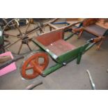 Vintage green painted wooden wheelbarrow with iron mounted wheel