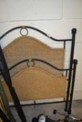 An iron framed and seagrass single bed