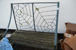 An iron framed garden bench with spiders web back