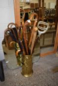 Brass stick stand with various sticks and umbrellas