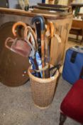 A wicker basket together with a quantity of walking sticks and umbrellas etc