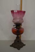 Cranberry glass oil lamp with cast iron base (a/f)