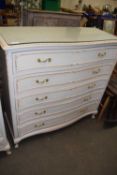 A cream and gilt decorated serpentine French style chest of drawers