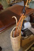 A wicker stick stand and various walking sticks