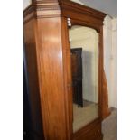 A late 19th Century mahogany wardrobe of unusual form with a moulded cornice, a central mirrored