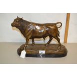 A contemporary bronzed metal model of a bull set on a polished marble base