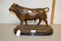 A contemporary bronzed metal model of a bull set on a polished marble base