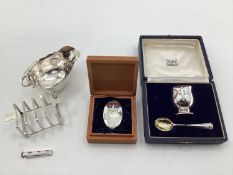A collection of sterling silver items to include toast rack, sauce boat, and other items