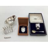 A collection of sterling silver items to include toast rack, sauce boat, and other items