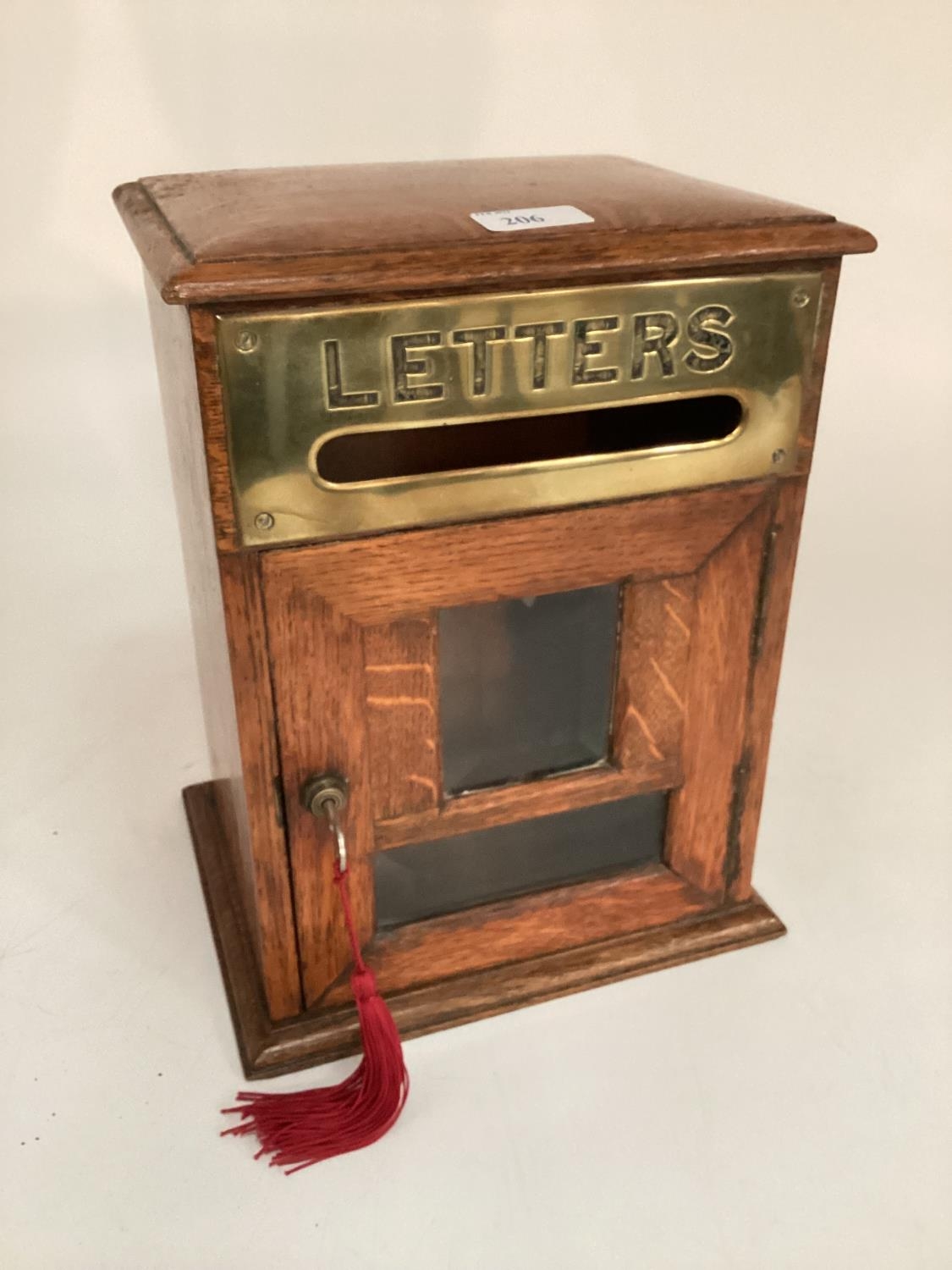 An early C20th letter or post box of oak construction with brass plate and bevelled glass single