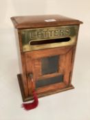 An early C20th letter or post box of oak construction with brass plate and bevelled glass single