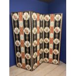 A three panelled folding upholstered screen, the front with a red and black pattern depicting