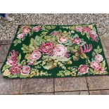 A tapestry rug, with green ground and pink roses