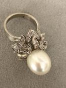 An 18c white gold, pearl and diamond ring, central single pearl, approx 12mm set with double
