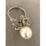 An 18c white gold, pearl and diamond ring, central single pearl, approx 12mm set with double