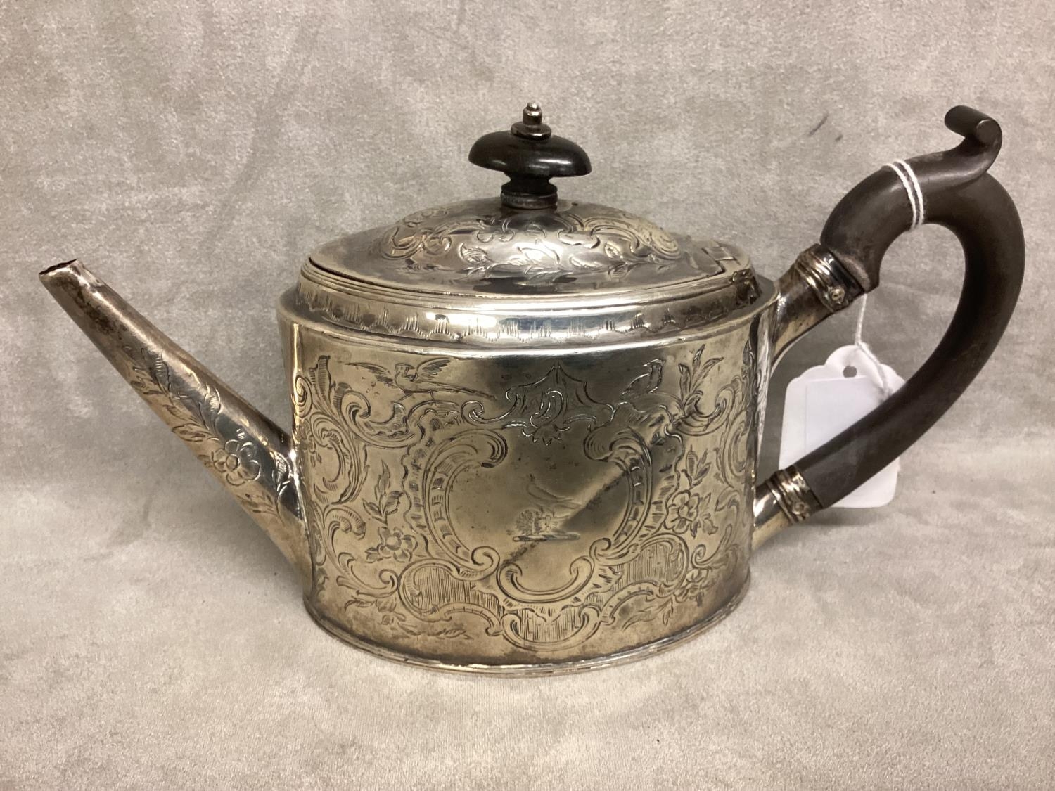 A Georgian Sterling silver Bachelors tea pot, ebonised handle with chased scrolling decoration by