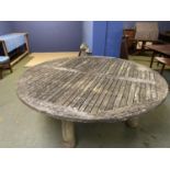 A large circular weathered garden table, 200cmD (one leg loose)