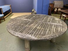 A large circular weathered garden table, 200cmD (one leg loose)