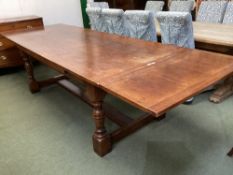 A large heavy oak extending dining table, with solid stretcher to base, 307cm with both ends.