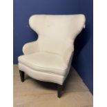 An oversized modern wing backed arm chair, upholstered in cream fabric and brass studded , 120cm H