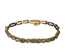 An unmarked yellow metal bracelet, set with graduated line of round cut blue zircons, in fitted box,