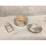 A collection of sterling silver items to include scallop dish, toast rack and wine coaster