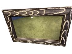 A decorative rectangular wall mirror, framed in a faux chenille brown and cream animal skin border