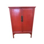 A C20th, Chinese style, two door cabinet on raised legs, with fitted interior, painted red 95cm W