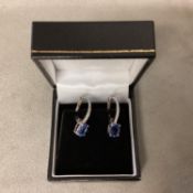 A pair of unmarked white metal, Tanzanite earings, with Bale set line of single cut diamonds