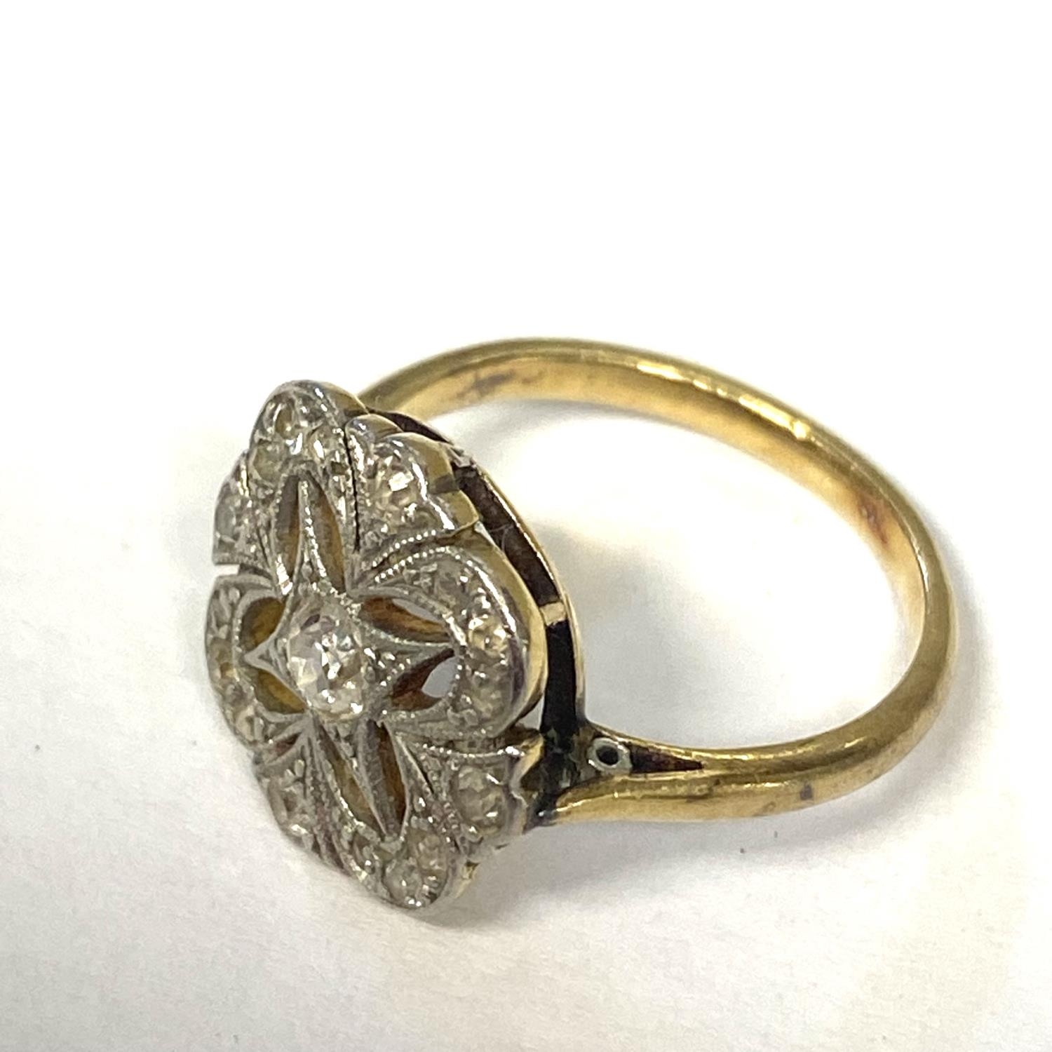 An unmarked white and yellow metal and diamond ring, pierced design with central old cut diamond