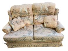 Modern two seater sofa, upholstered in a cream fabric with an oriental themed design of blue fauna