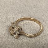 An unmarked (rubbed) yellow and white metal diamond set flower ring, size L