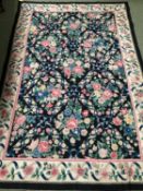 A needlepoint rug, of dark ground and all over rose pattern, 2.74 x 1.83, bears label Needlepoint,