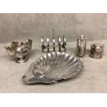 A collection of Sterling silver items to include a scallop dish, toast rack, condiments, various
