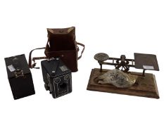 Two vintage box Brownie cameras together with a pair of vintage postal scales on wooden plinth