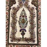 Small cream ground rug, with all over green and multicolour boarder and central vase and flower
