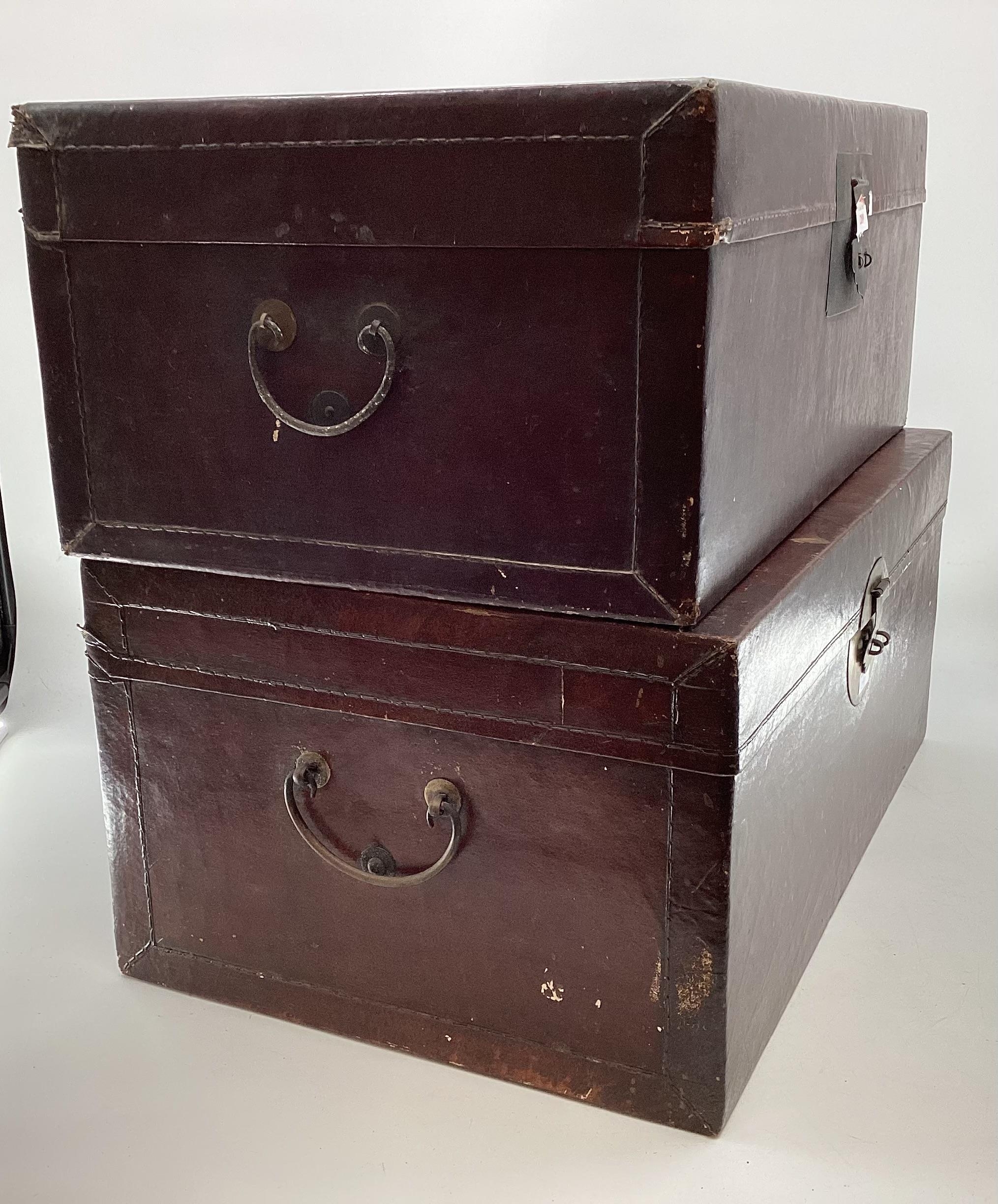 A near pair of Chinese C19th style lacquer trunks with fabric lined interiors and brass carry