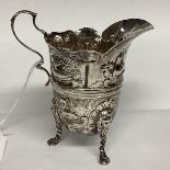 A Sterling silver cream jug, decorated with repousse farmyard scenes on 3 paw feet by John