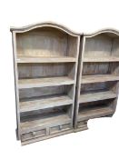 A pair of vintage chalk painted and distressed arch topped open bookcases, four fitted shelves