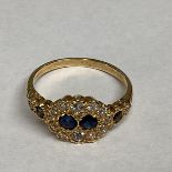 An unmarked yellow metal diamond and sapphire ring two central round cut sapphires with a surround