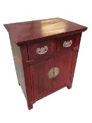 A Chinese red lacquered wedding cabinet, two short drawers over two cupboard doors, with brass