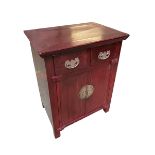 A Chinese red lacquered wedding cabinet, two short drawers over two cupboard doors, with brass